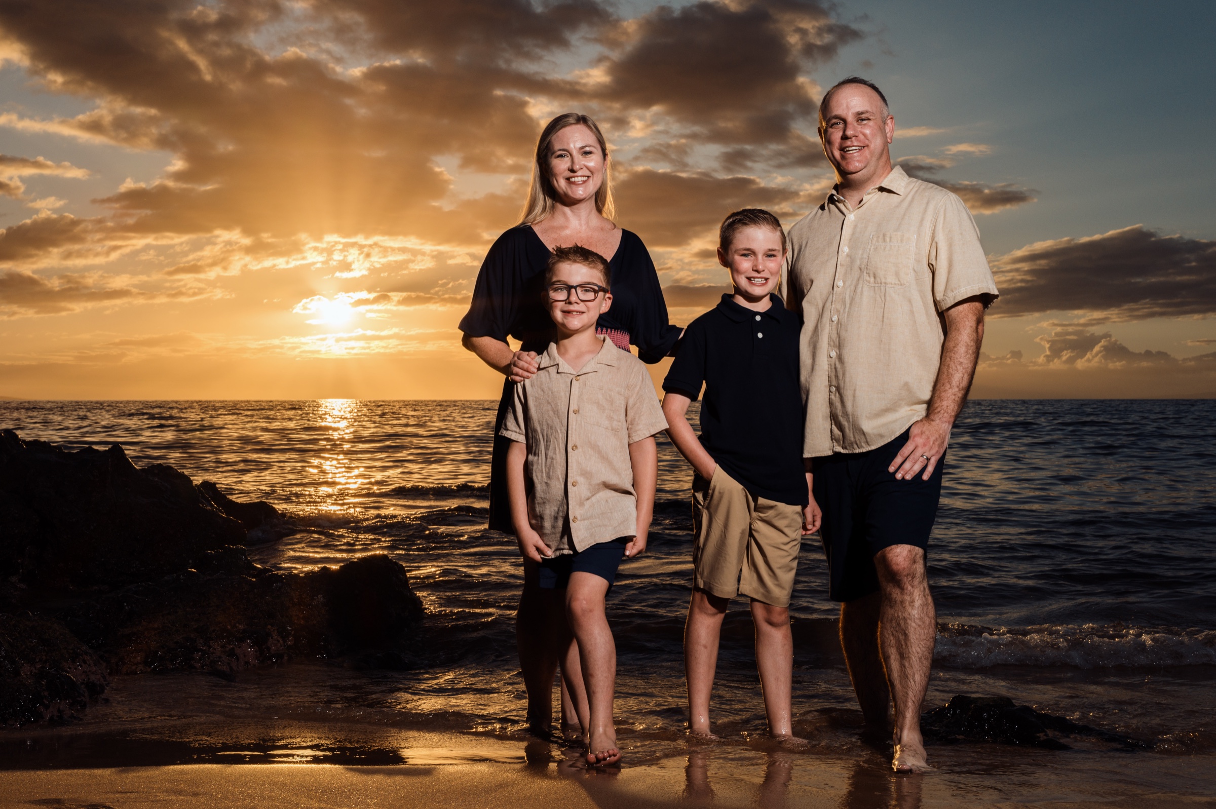 Family portrait against a dramatic golden Maui sunset