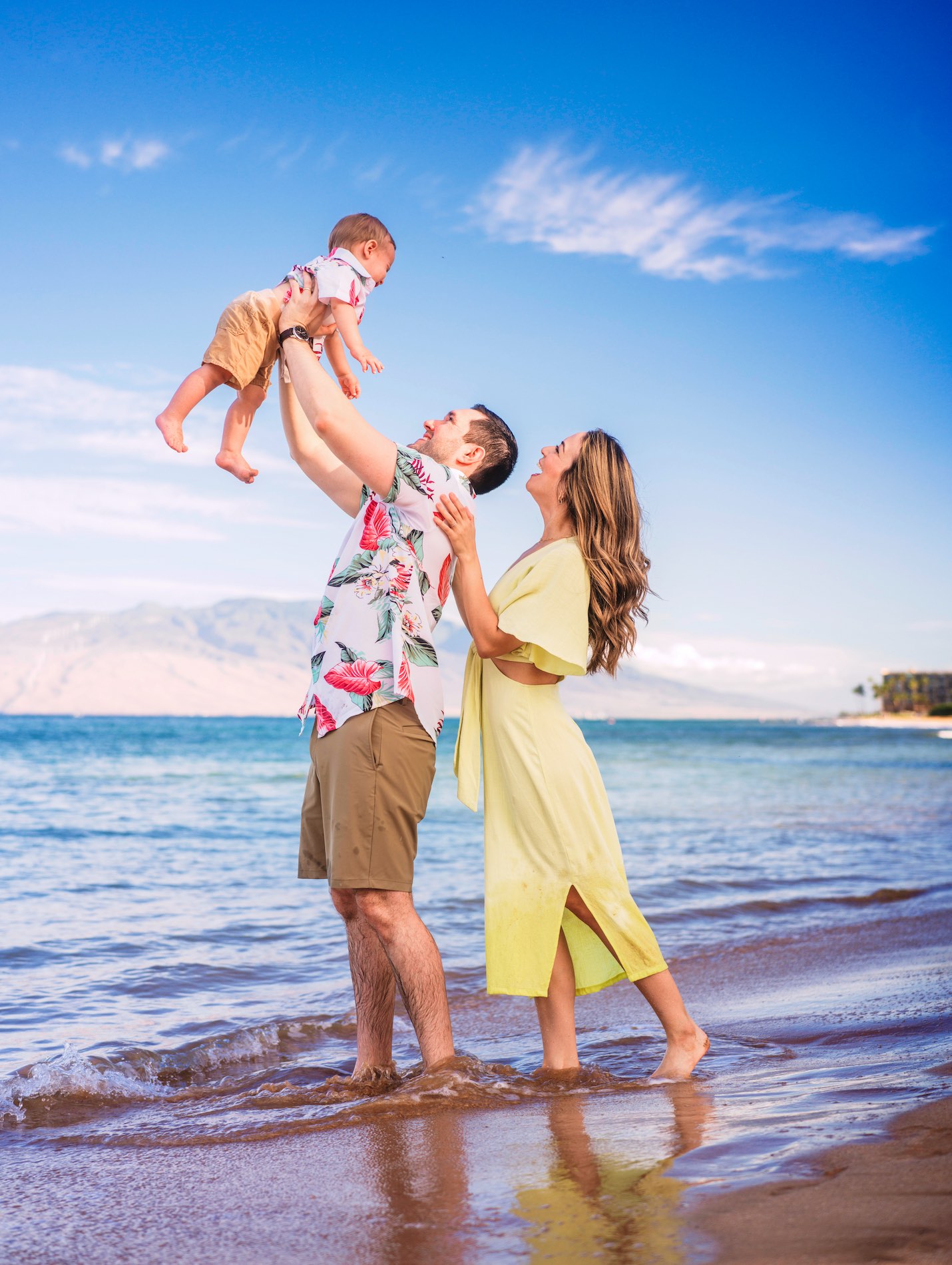 Family holding young toddler up in the air on a sunny Wailea beach