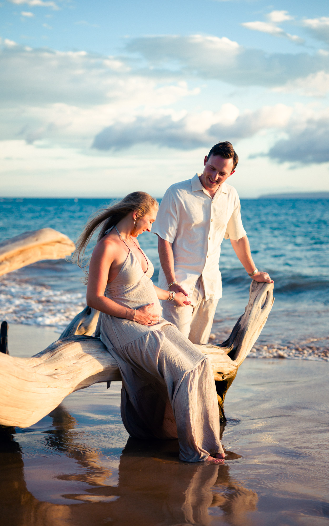 Couple leaning against driftwood in the shallows at sunset in Maui - image by Wailea Photo®