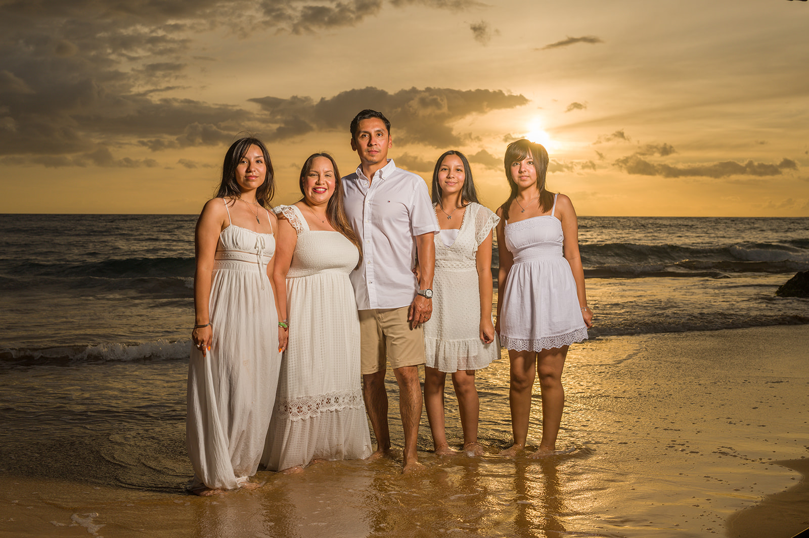A family in white attire on a Wailea beach at sunset