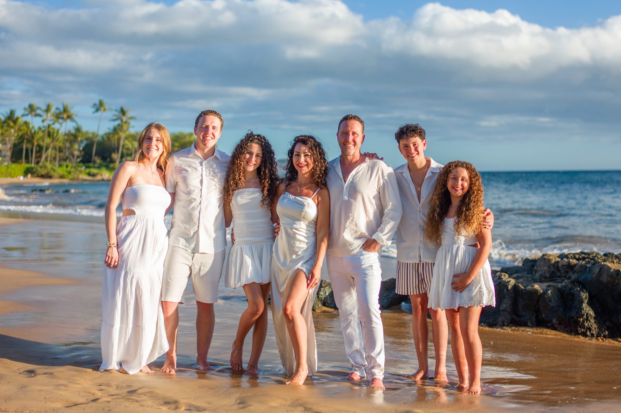 A family in coordinated white outfits on a Wailea beach in soft morning light