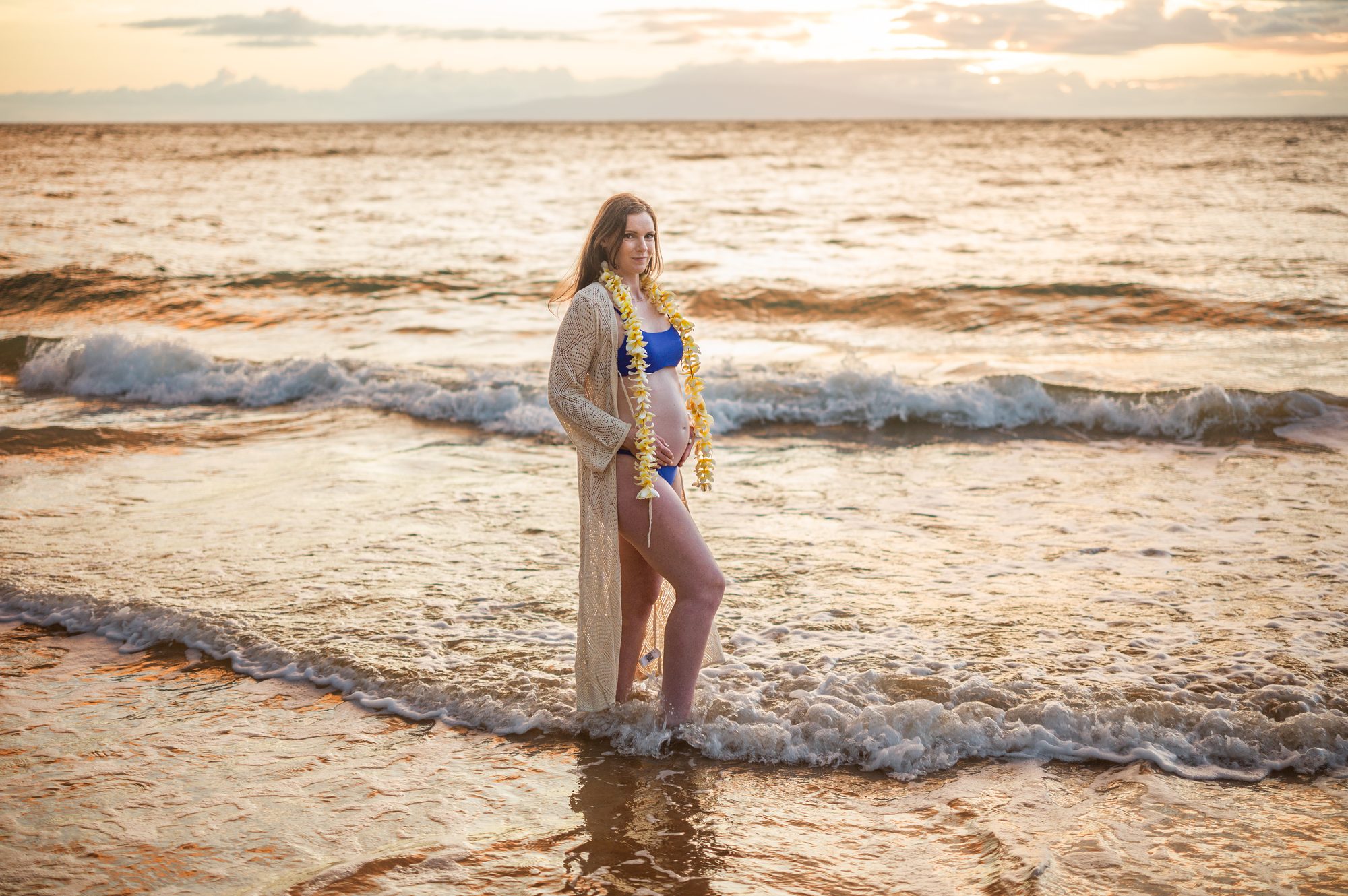 An expecting mother in the surf at sunset in Wailea