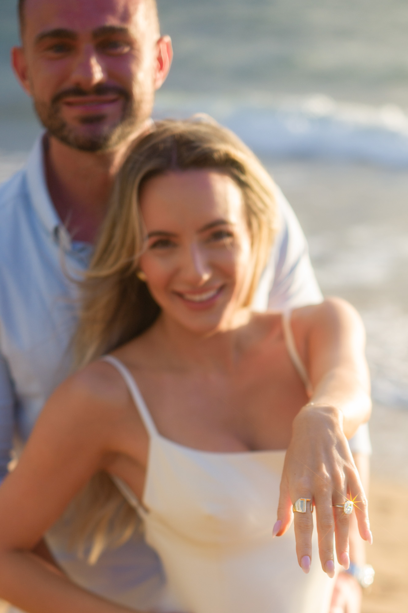 Surprise proposal in Wailea as photographer signals man to get down on one knee behind oblivious partner