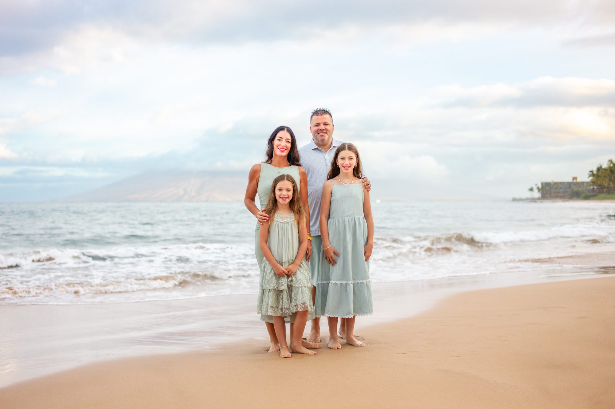 A family in white outfits smiling on a Wailea beach at sunrise