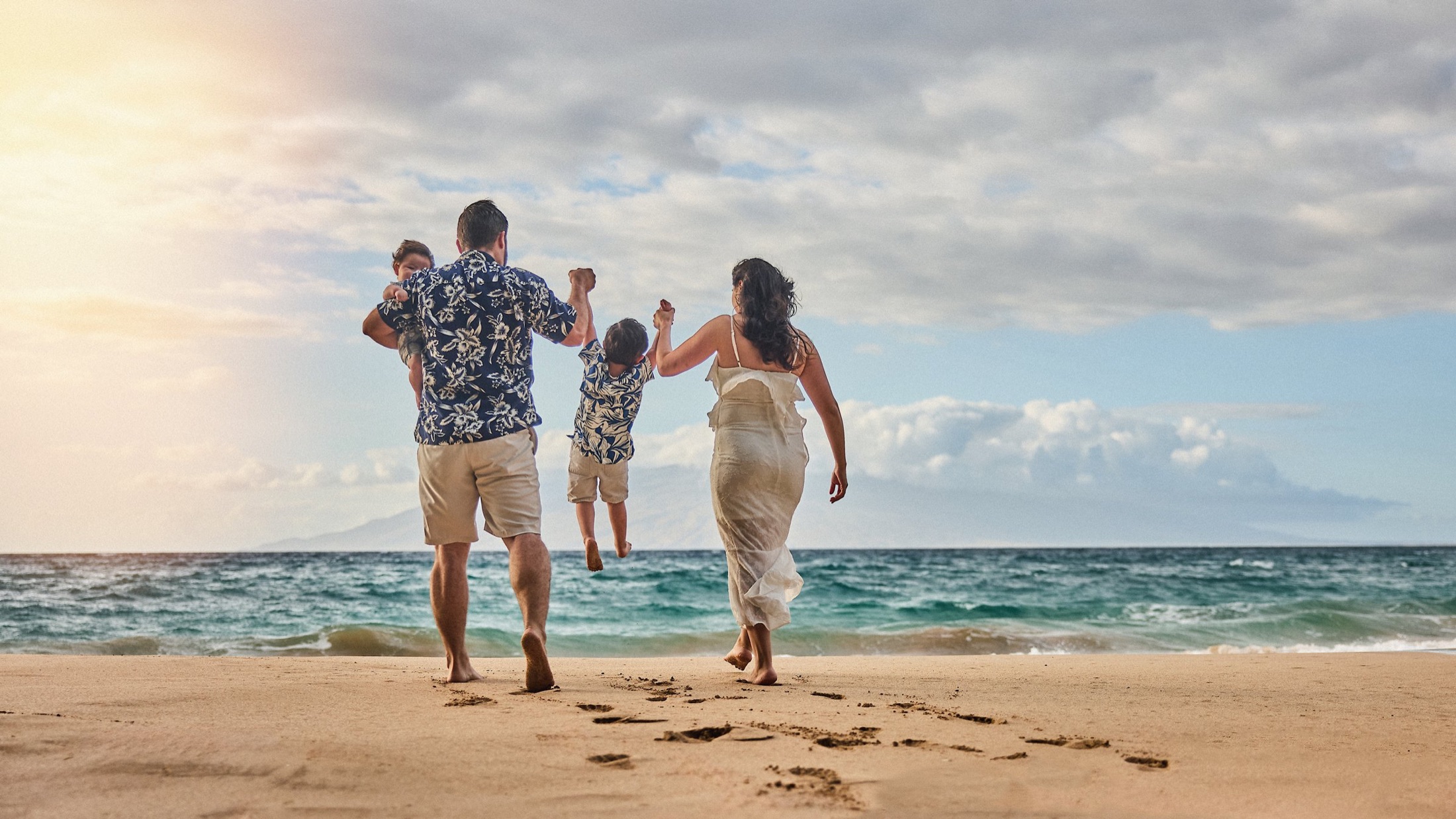 A family walking toward the ocean together during their Maui portrait session