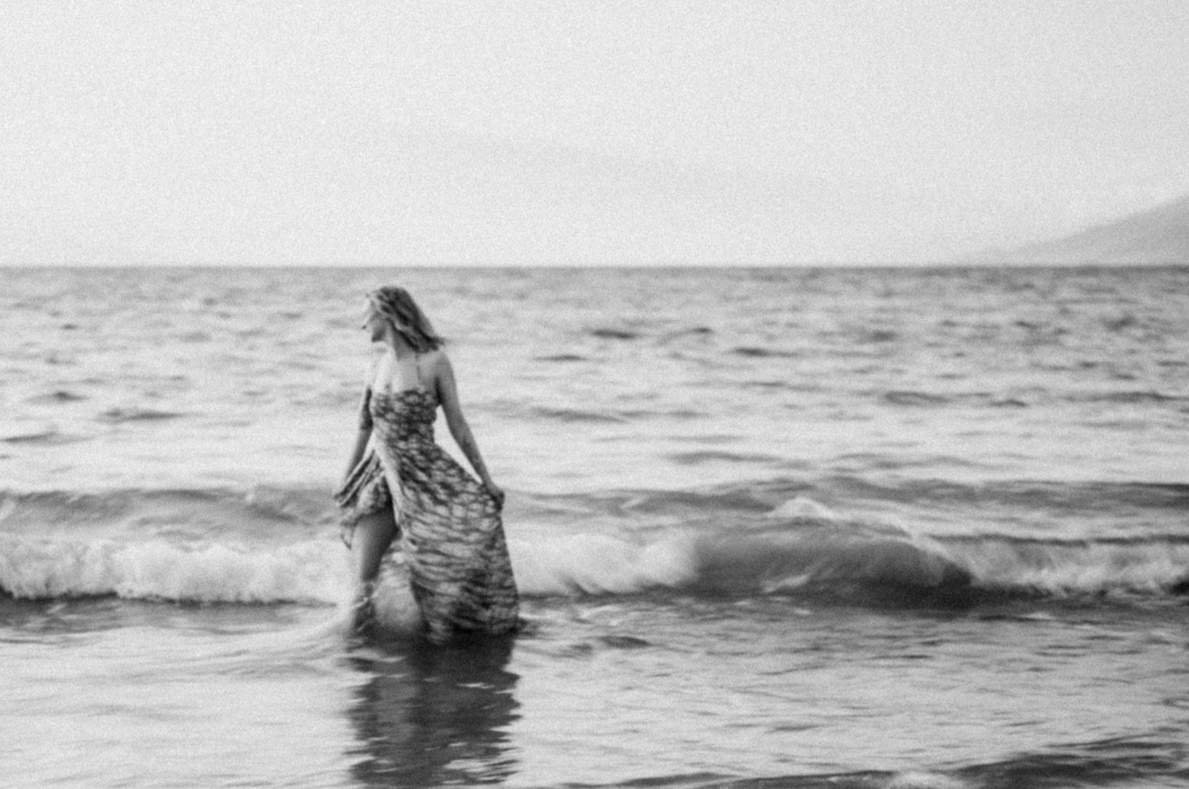 Woman walking through the Maui ocean in a black-and-white portrait