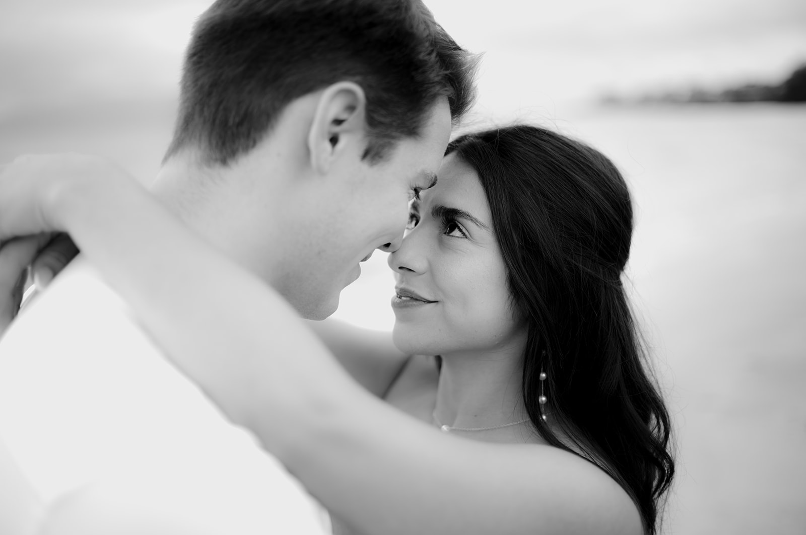 Close portrait of a couple forehead to forehead, her eyes looking up at him, in black and white