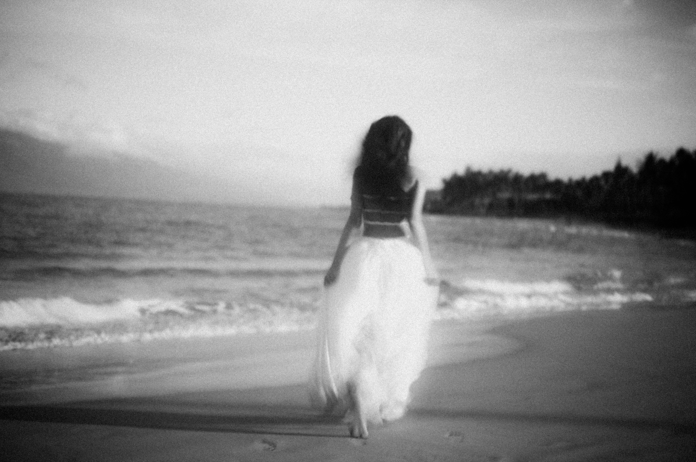 Dreamlike monochrome portrait of a woman walking at the edge of the Maui ocean