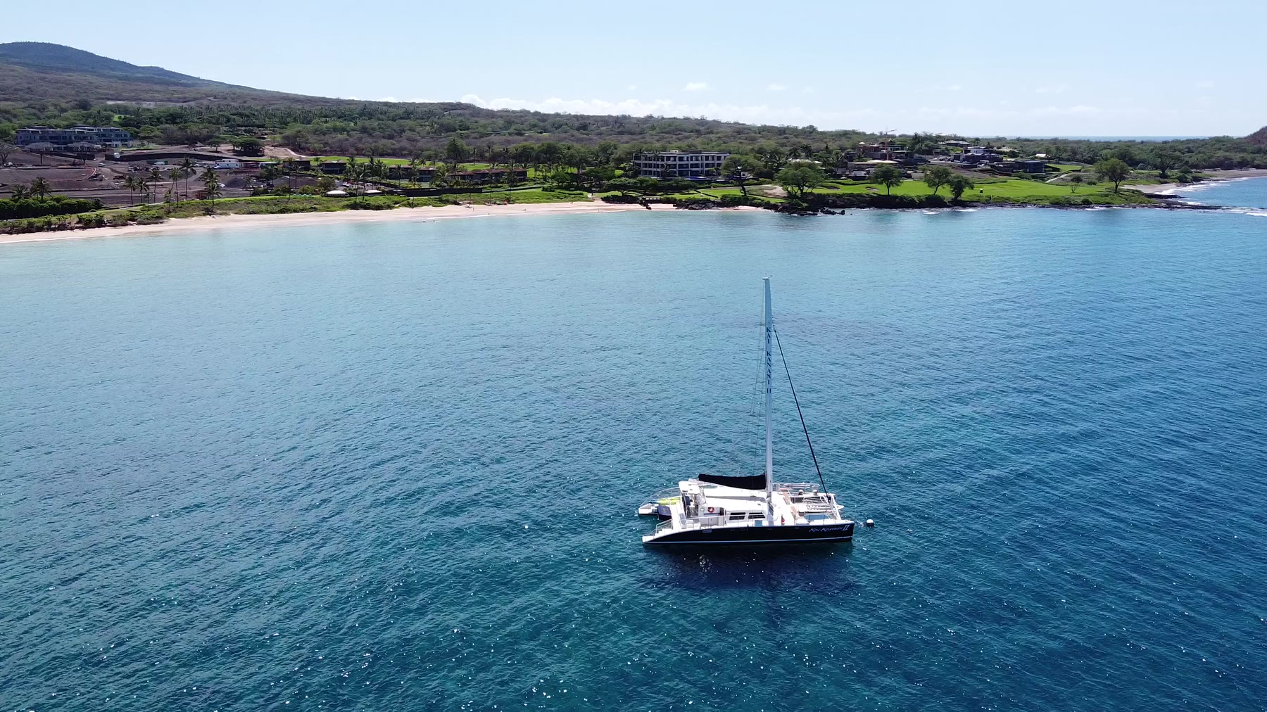 Catamaran seen from above with Makena beach and shoreline behind it