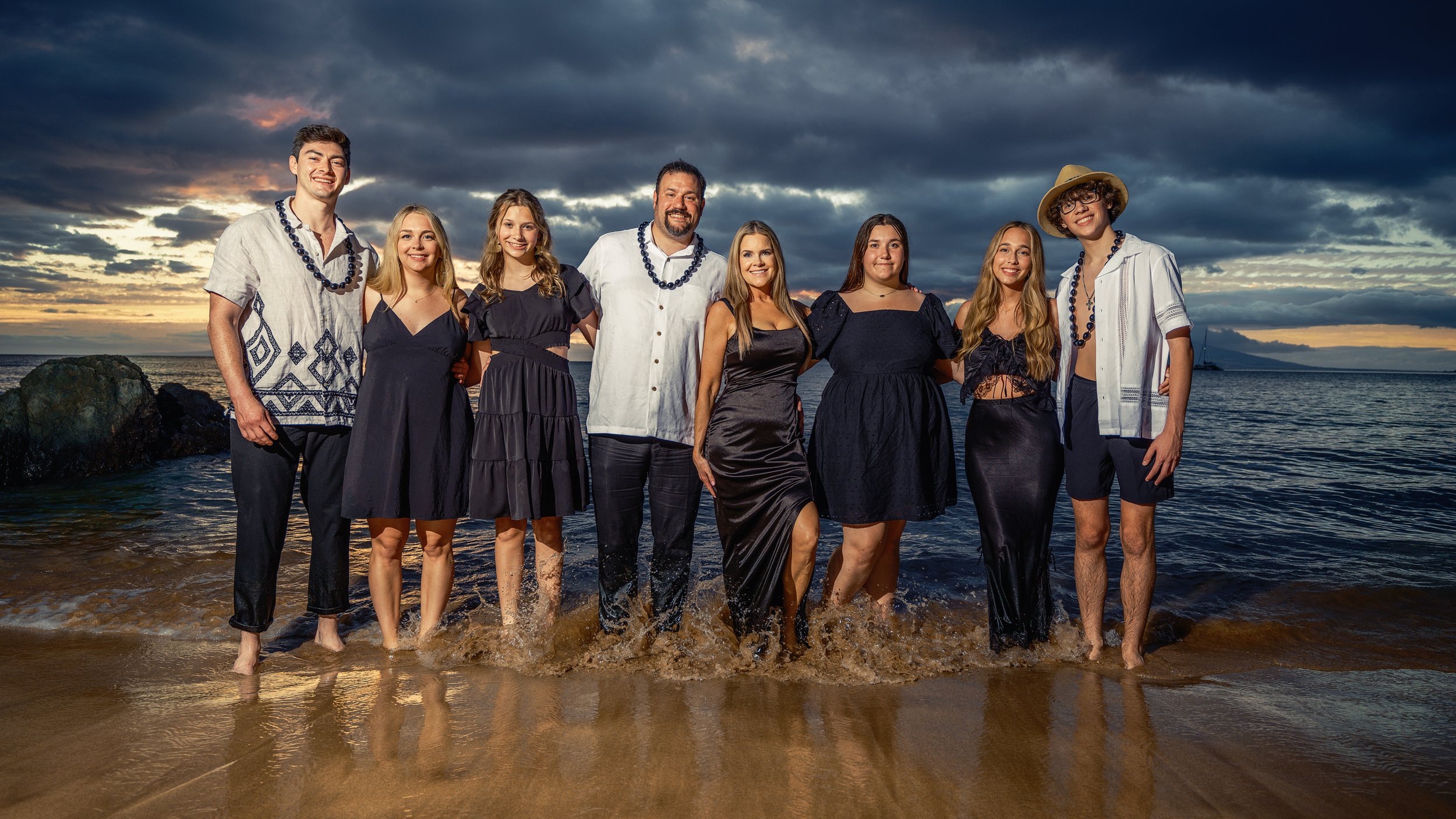 Large family wearing coordinated navy and white clothing during a dramatic Maui sunset portrait