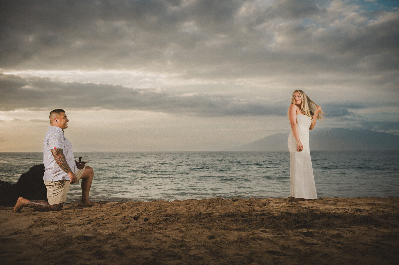 A surprise proposal at Maluaka Beach in Makena, Maui — the photographer positioned at a right angle to capture the boyfriend kneeling behind his unsuspecting partner