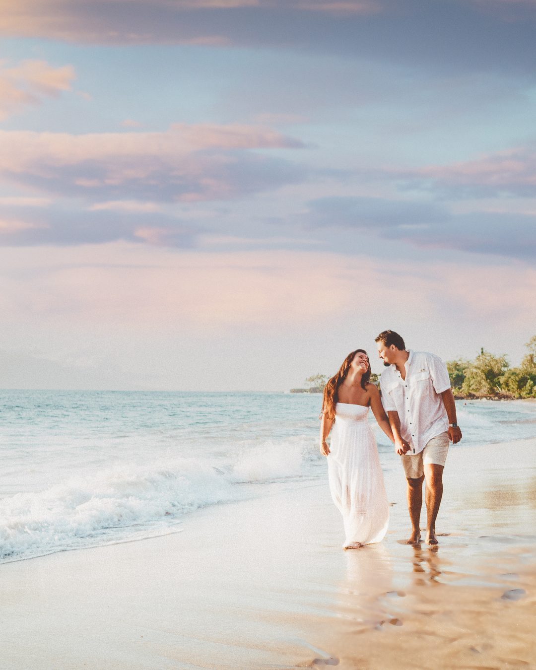 A couple walking the beach near the Fairmont Kea Lani at sunset