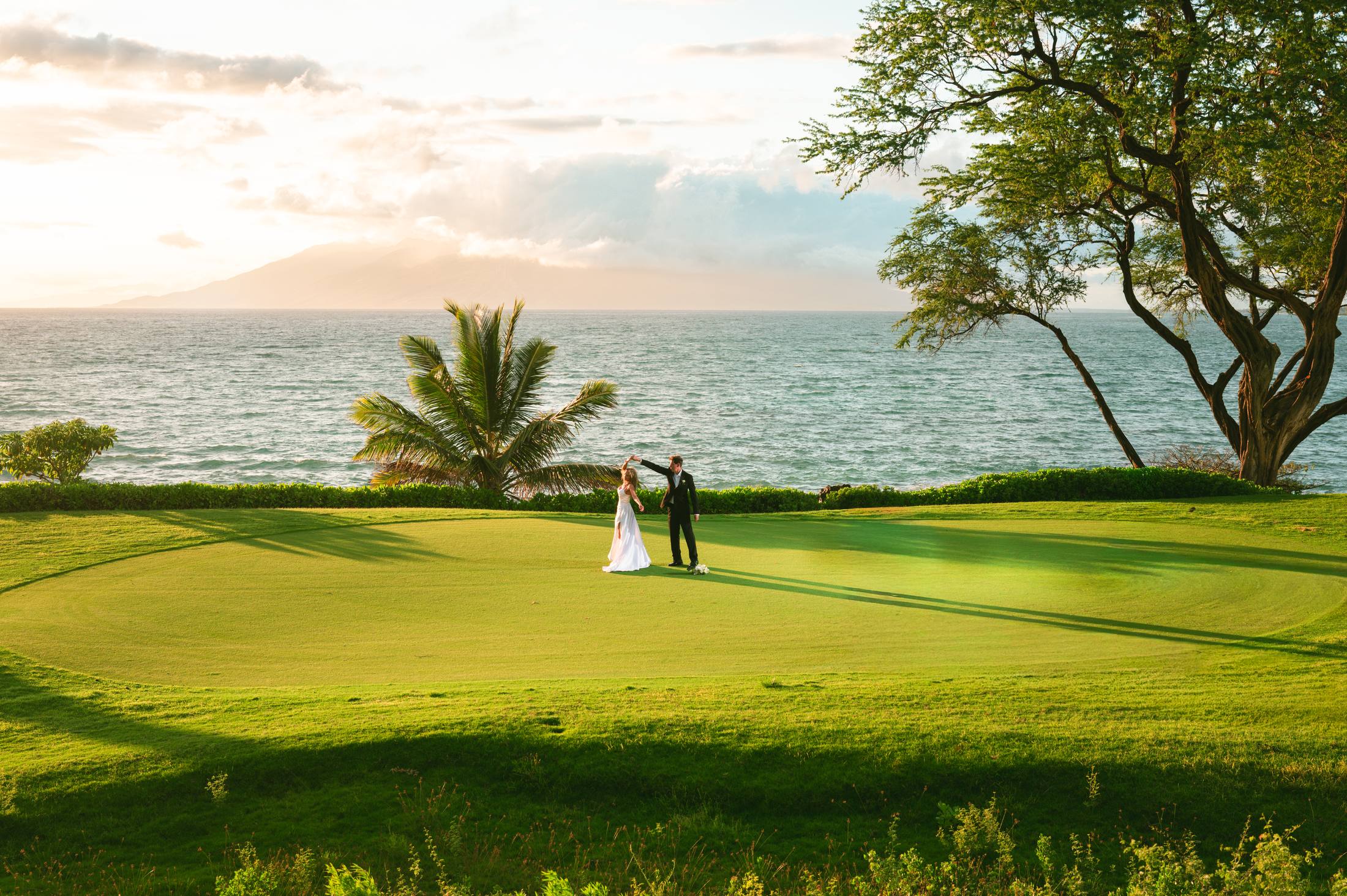 A newlywed couple in an expansive oceanfront Maui landscape
