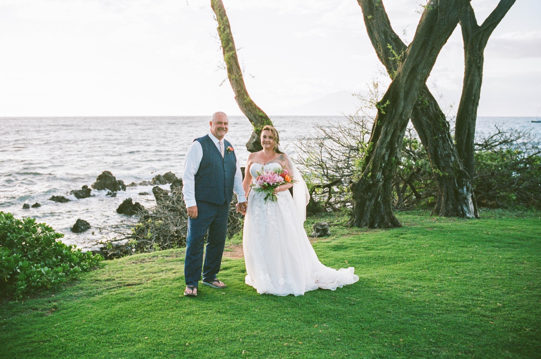 Bride and groom standing on the grass near the three-tree wedding location at Maluaka Beach