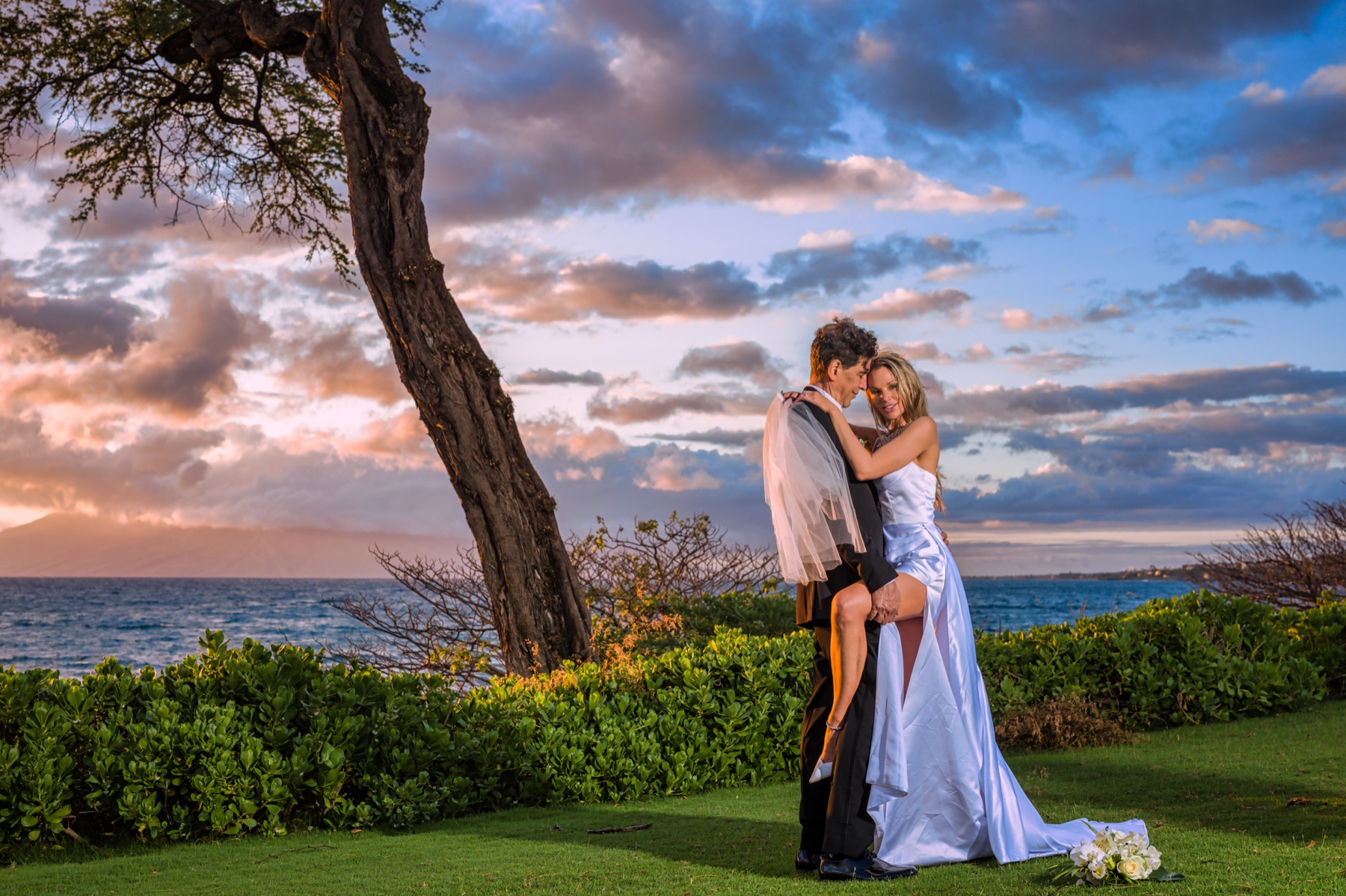 Wedding couple photographed beside the trees and ocean at Maluaka Beach in Makena