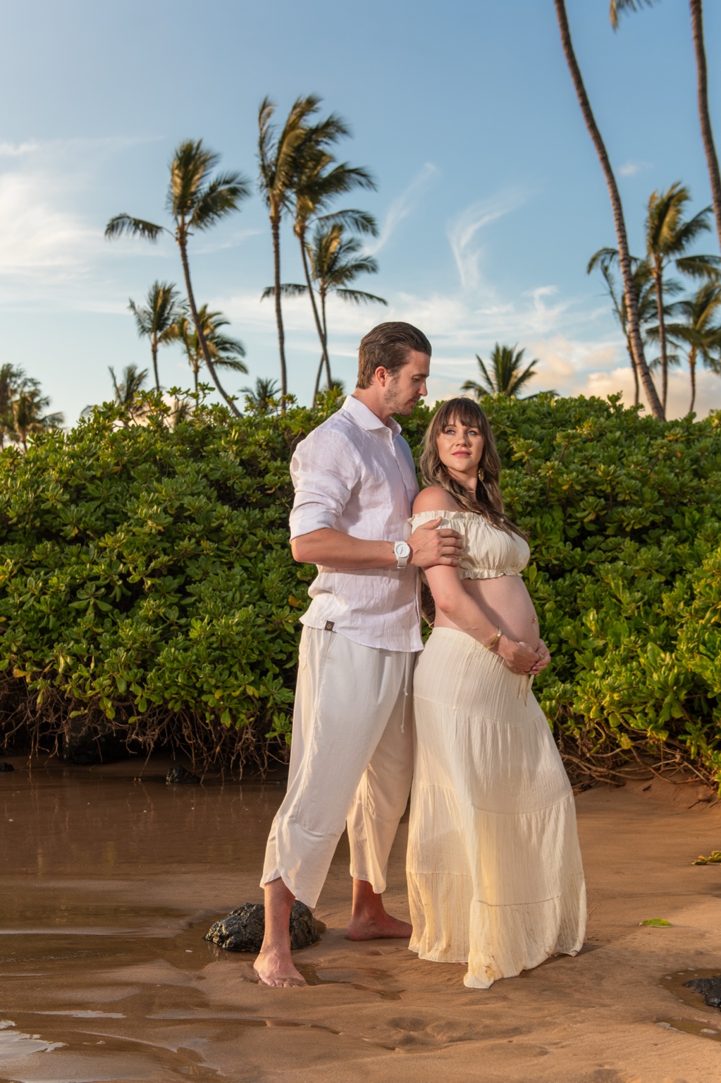 A maternity portrait beneath dramatic Maui clouds