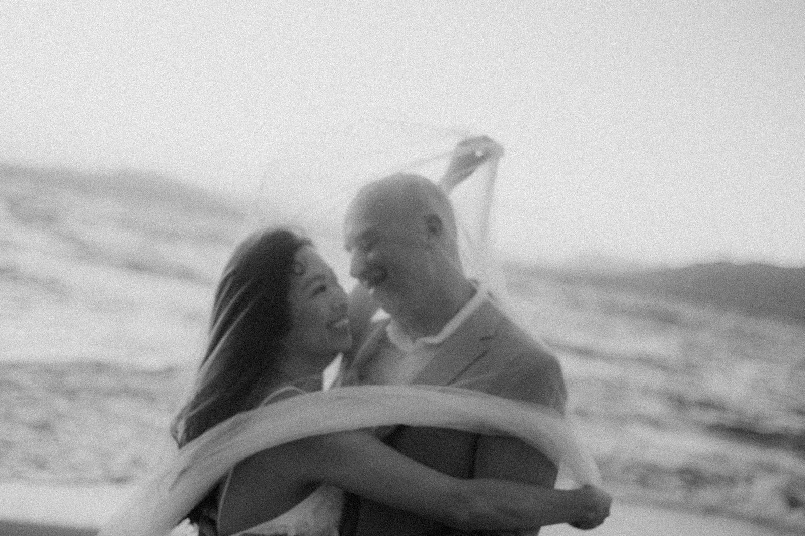 Black and white photograph of newlyweds embracing close together on a Maui beach