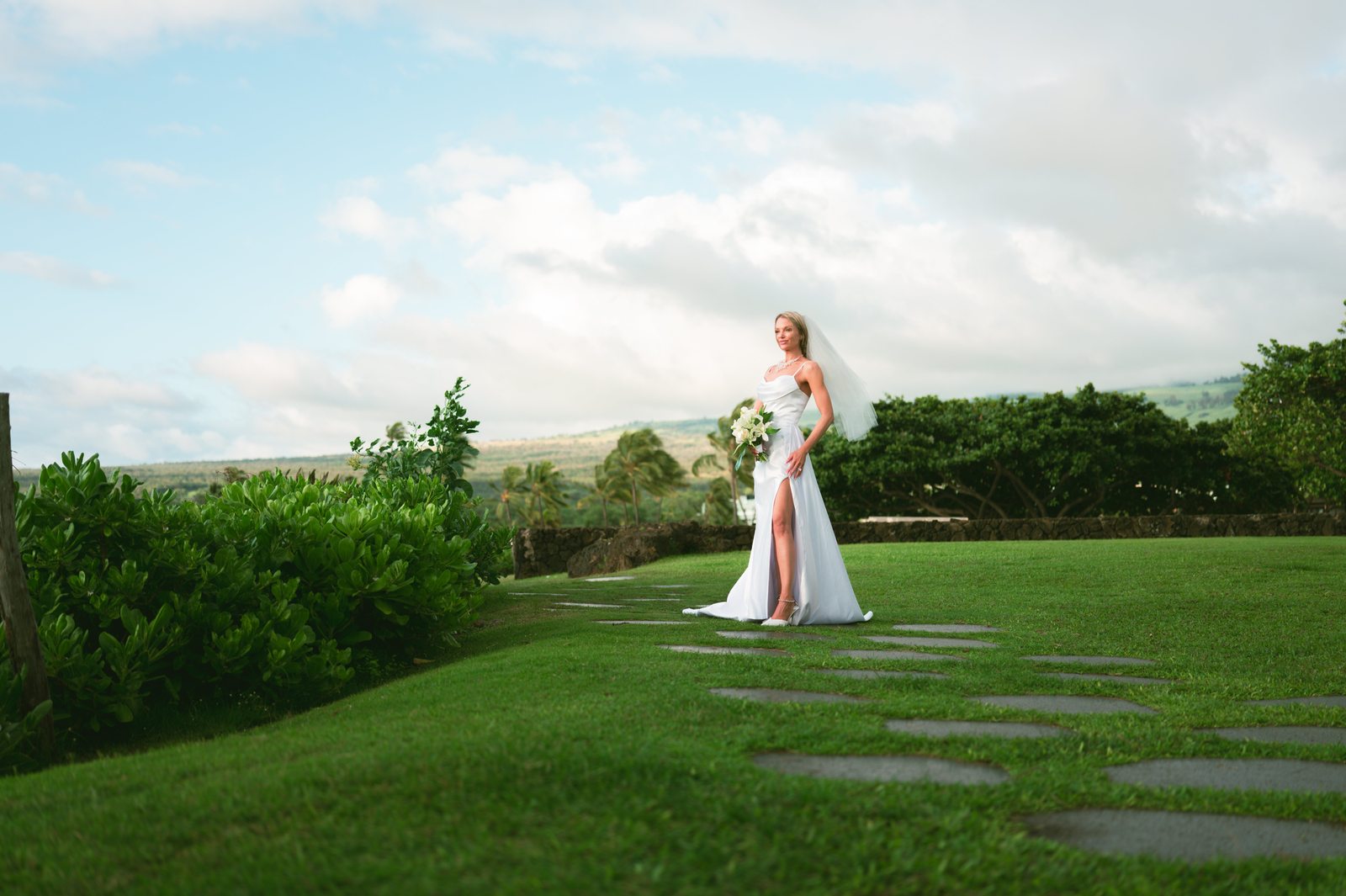 A bride and groom with their wedding party gathered on an oceanfront lawn in Maui