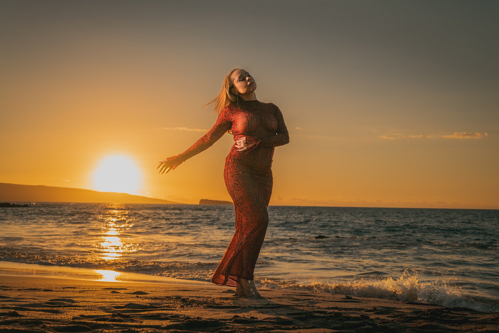 Woman in a red dress photographed at sunset on a Maui beach after protecting her skin from the sun
