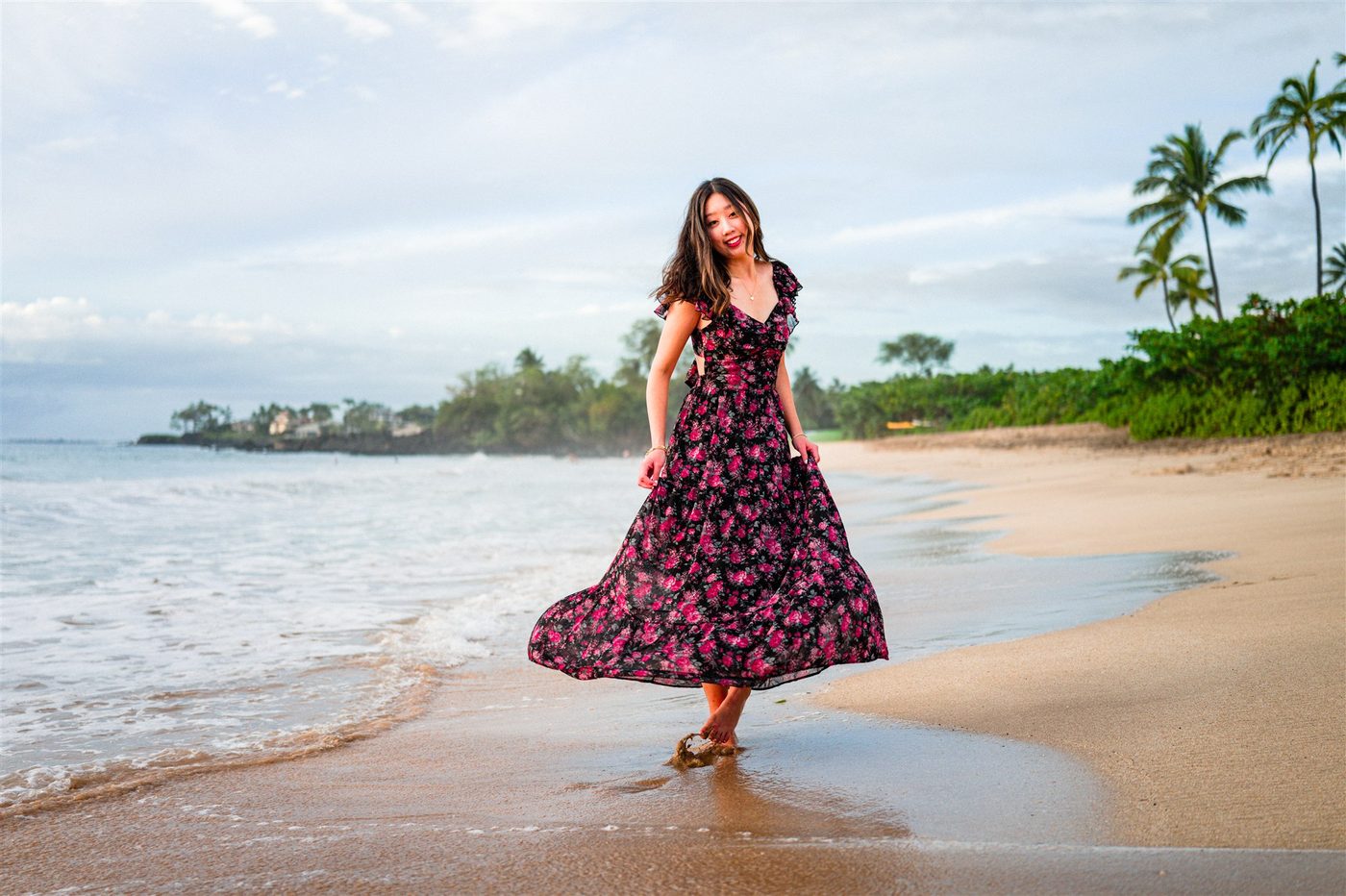 A senior walking the shoreline in a dark floral dress at Maluaka Beach