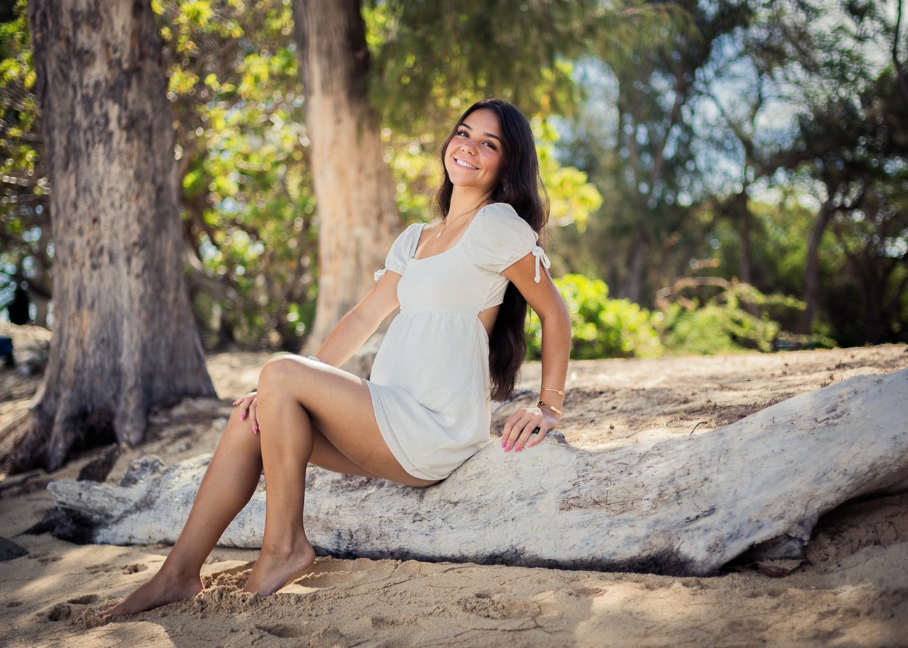 A senior seated on a fallen log among ironwood trees in Wailea
