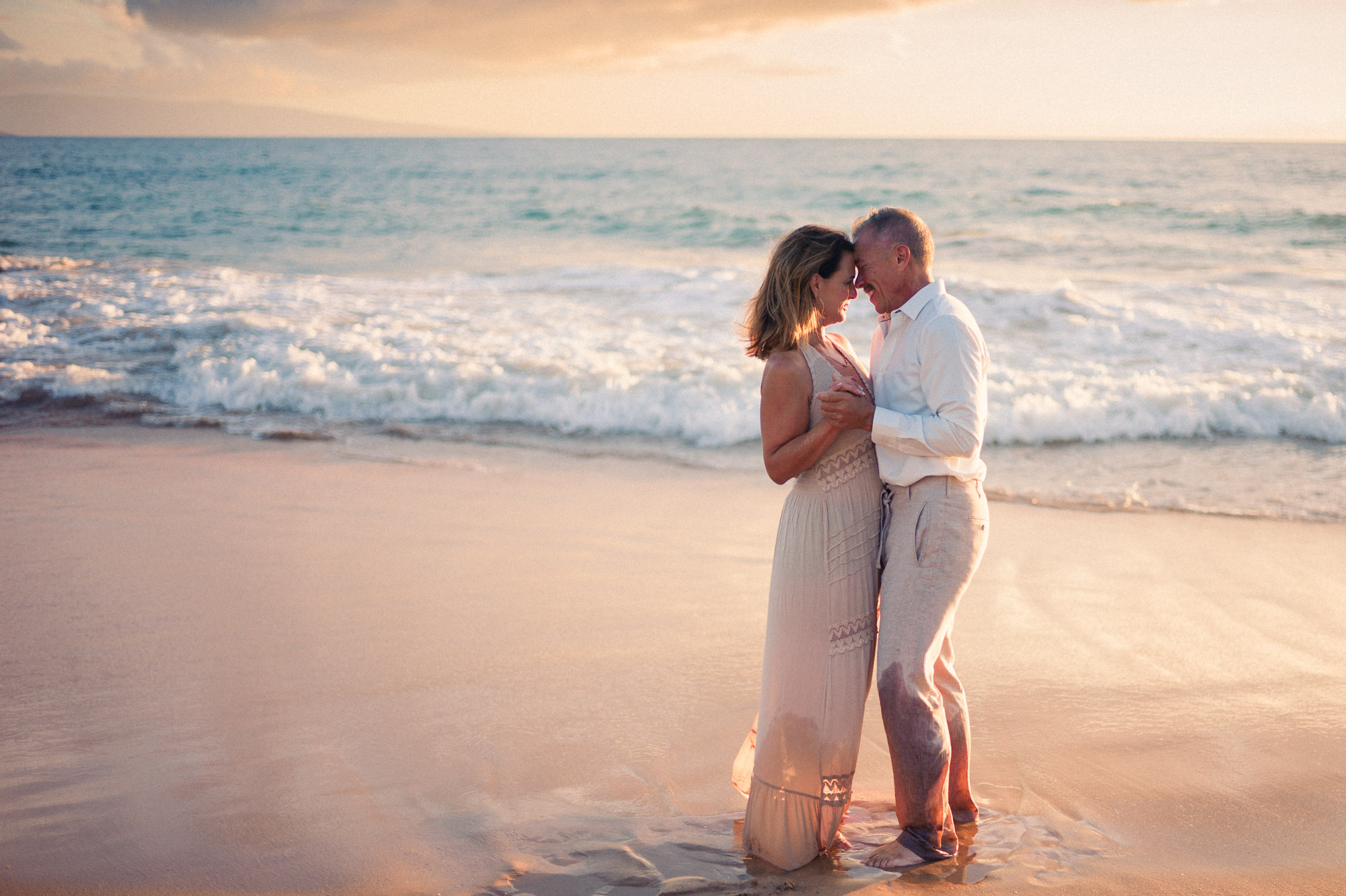Couple standing forehead to forehead in shallow water at sunset in South Maui - image by Wailea Photo®