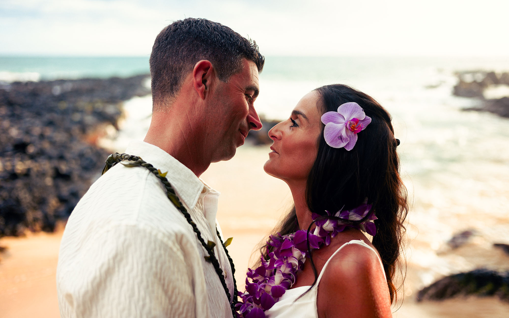 Close portrait of a couple with orchid lei at sunset on the Maui shoreline - image by Wailea Photo®