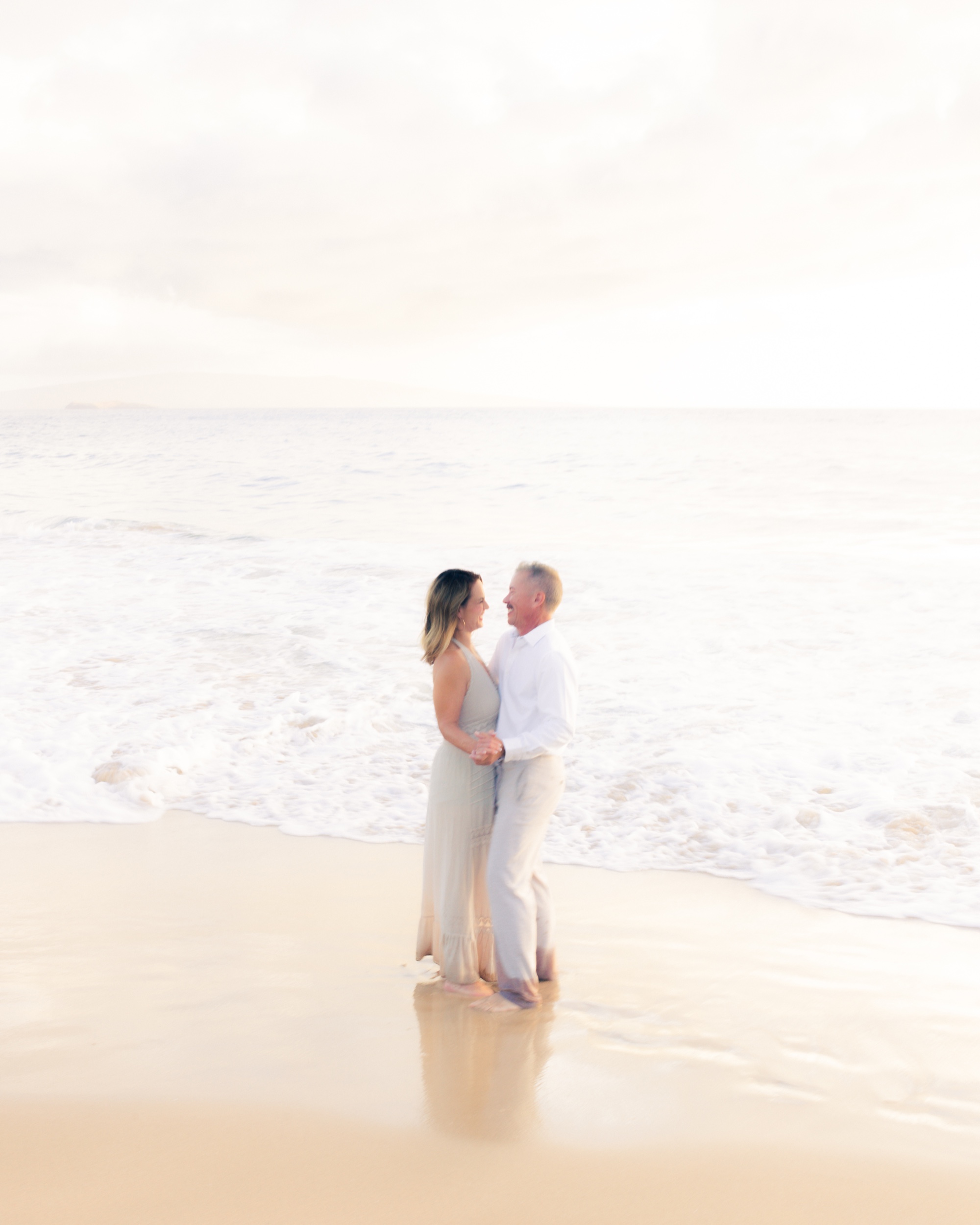 A couple dancing together at the shoreline in Wailea
