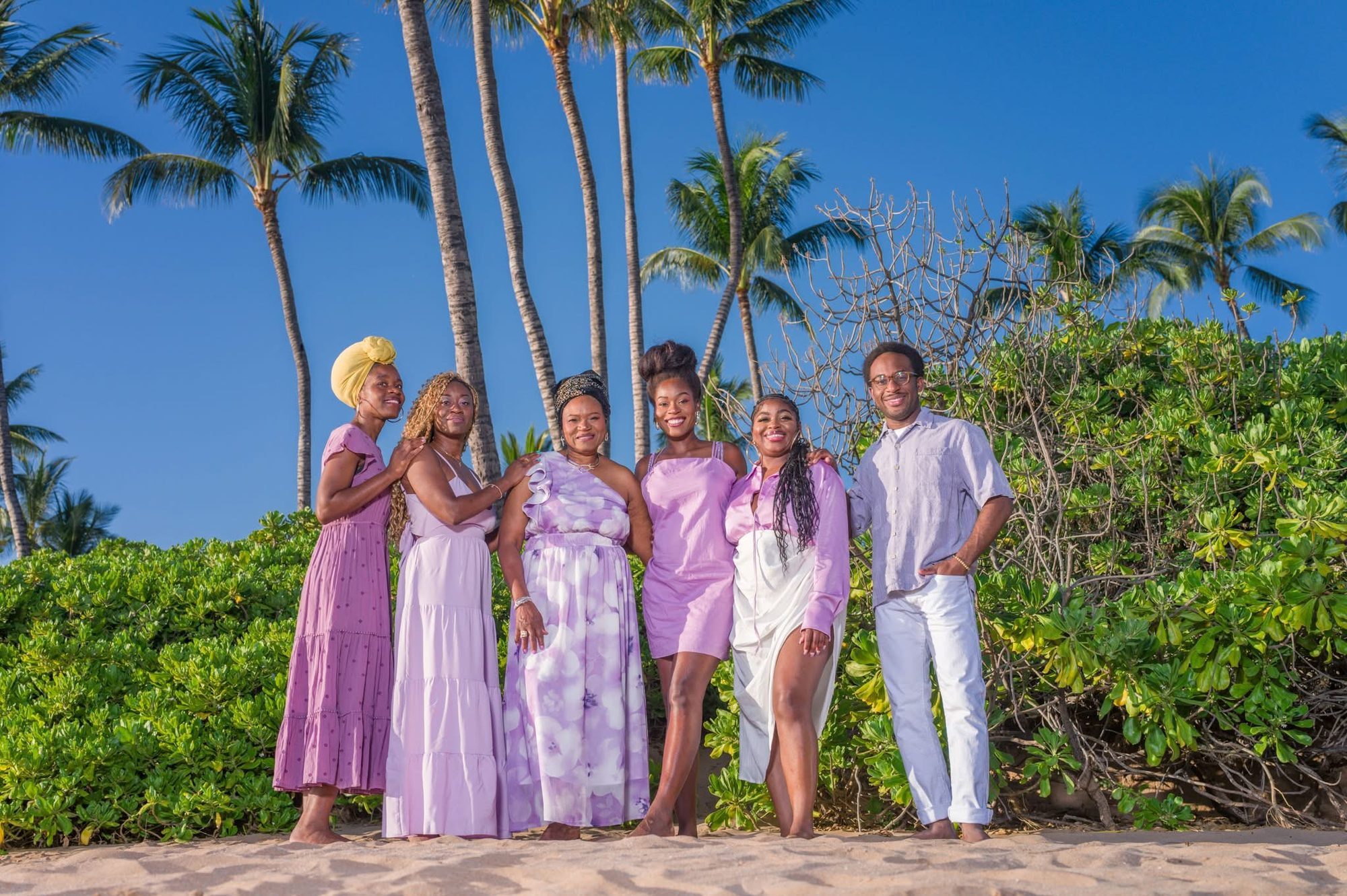 A family in coordinated purple and lavender outfits among palm trees in Wailea