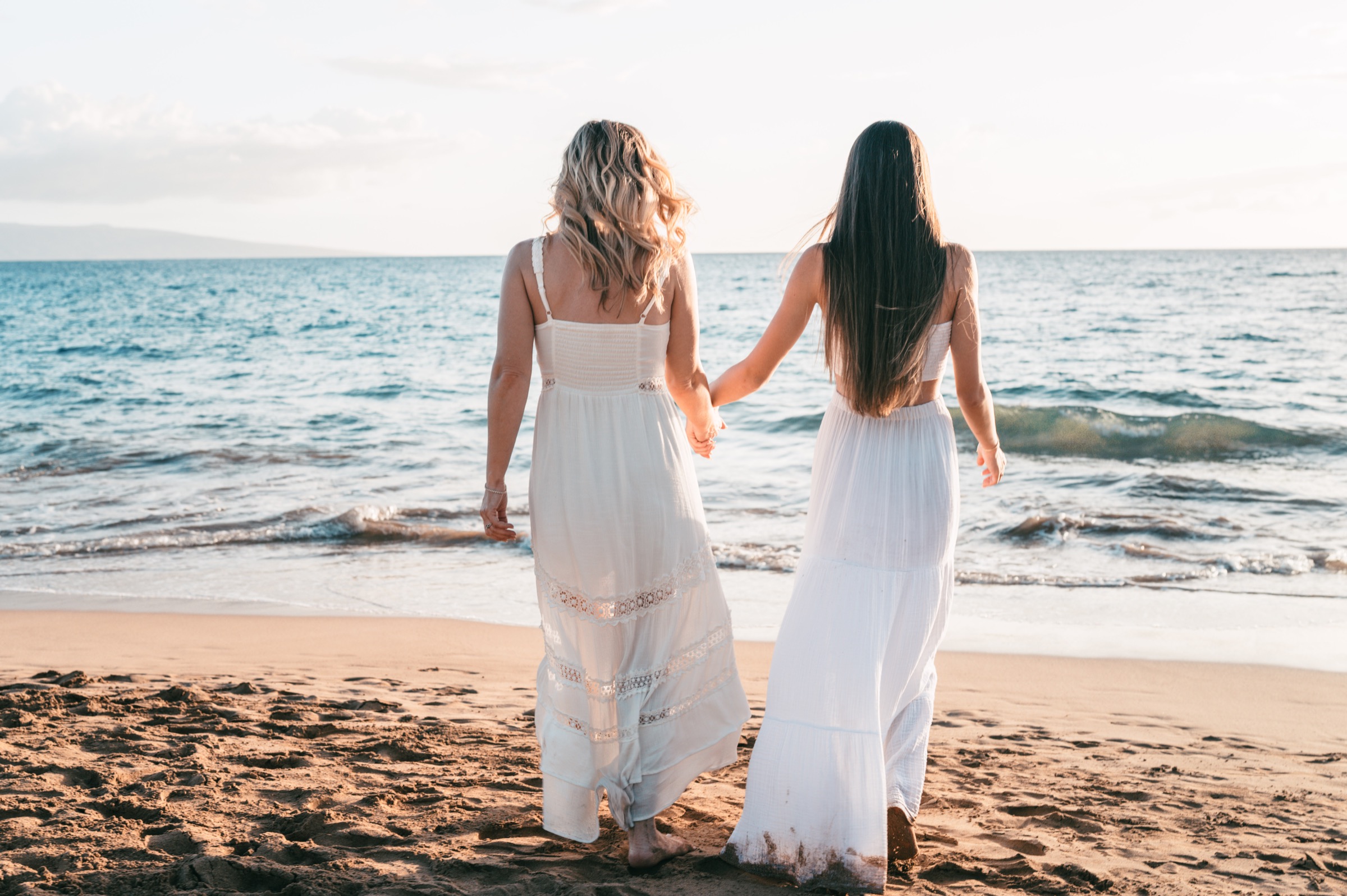 Family wearing coordinated white and ivory clothing for a sunrise Maui beach photo session