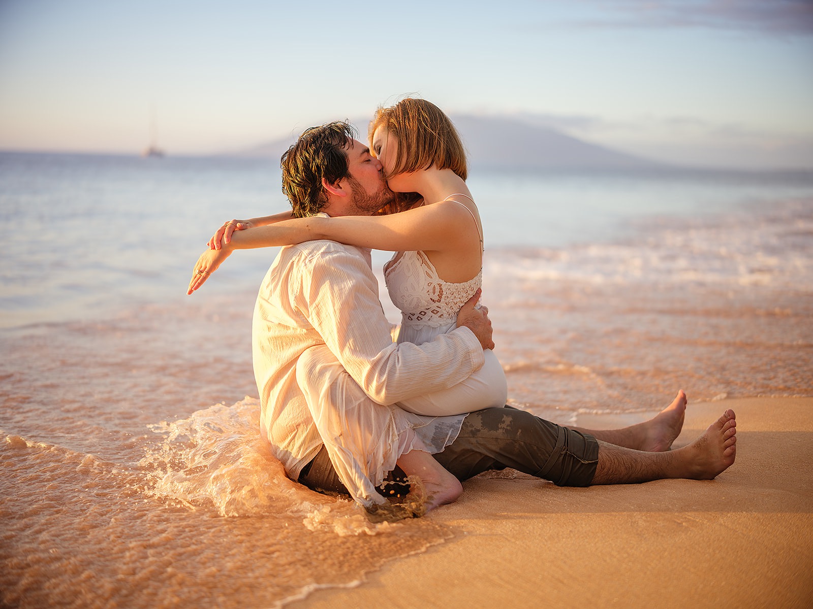 A couple kissing in the shallow surf at sunset in Maui