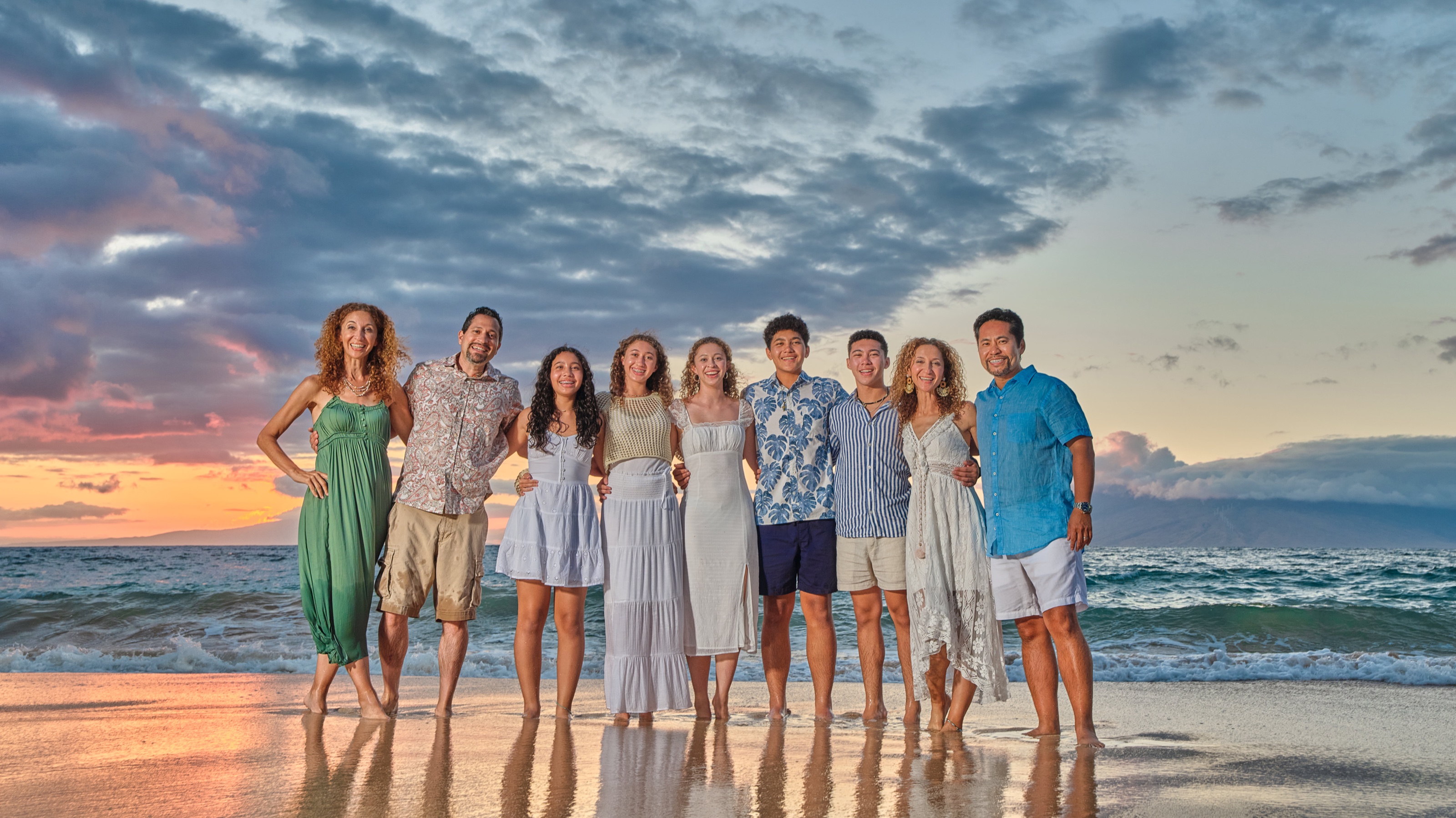 A large family in coordinated colors photographed on a Maui beach at sunset